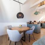 Rundtisch mit vier Stühlen, Küchenbereich und Sofa im offenen Raum.