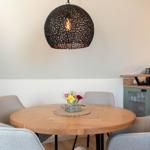 Runder Holztisch mit vier Stühlen unter einer Hängelampe.