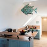 Küche mit Holzoberflächen und blauen Schränken. An der Decke hängt ein Fischobjekt.