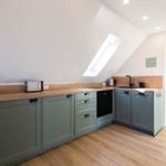 Küche mit grünen Schränken, Holz Arbeitsplatte und Dachfenster.