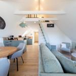 Wohnung mit Essbereich, Sofa und Treppe zur oberen Etage.