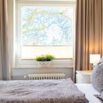 Schlafzimmer mit Bett, Fenster und Pflanze auf dem Sims.
