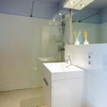 Badezimmer mit Dusche, Waschbecken und Spiegel.