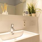 Waschbecken mit Spiegel, Pflanze und Aromalampen