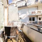 Terrasse mit Tisch und Stühlen, Sicht auf Wohnhaus mit Balkonen.