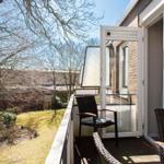 Terrasse mit Sitzgelegenheiten und Blick auf Garten und Bäume.