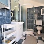 Badezimmer mit Dusche, Toilette und Waschbecken. Fliesenboden und Wandfliesen.