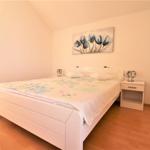 Schlafzimmer mit weißem Bett, Nachttisch und Wandbild mit Tulpenmotiv.