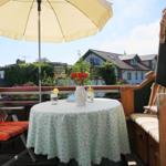 Terrasse mit Tisch, Stühlen und Sonnenschirm. Blick auf Wohnhäuser und Grünflächen.
