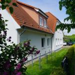 Weiße Villa mit rotem Dach, umgeben von grüner Wiese und blühenden Lilien.