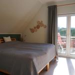 Schlafzimmer mit Dachschräge, Bett, Balkonzugang und Holzregal.