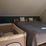 Schlafzimmer mit Doppelbett und Babybett. Wand mit Holzscheiben. Dachneigung sichtbar.