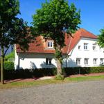 Weiße Villa mit rotem Dach und Bäumen im Vorgarten.