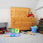 Kinderzimmer mit Holztruhe, Spielzeug und Falttisch.