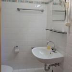 Badezimmer mit Waschbecken, Spiegel, Toilette und Handtuchhalter.