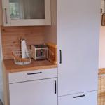 Küchenbereich mit weißen Schränken, Holzoberfläche und Toaster.