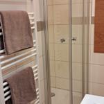 Badezimmer mit Duschkabine, Heizkörper und Waschbecken.