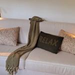 Ein Sofa mit Kissen und einer Decke, an den Wänden hängen Wandlampen.