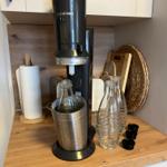 Sodastream-Gerät mit Gläsern und Zubehör auf Küchenarbeitsfläche.