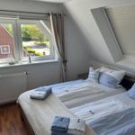Zimmer mit zwei Betten, Dachfenster und Blick auf Garten.