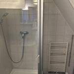 Dusche mit Duschbrause, Handtuchhalter und Heizkörper an der Wand.