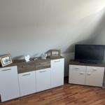 Schlafzimmer mit Holzboden, Schrank und Fernseher auf einem Möbelstück.