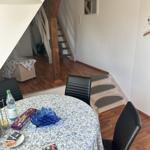 Rundtisch mit Tischdecke, Stühle und Treppenaufgang im Hintergrund.