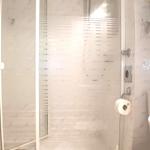 Badezimmer mit Dusche, Waschbecken und Heizung.