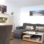 Wohn- und Essbereich mit Sofa, Tisch und Stühlen. Wandbild zeigt Strand.