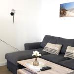 Ein Wohnzimmer mit grauem Sofa, Holztisch und Wandbild