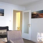 Wohnzimmer mit Sofa, Wandbildern und Blick in Schlafzimmer.
