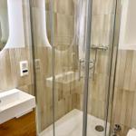 Badezimmer mit Dusche, Waschbecken und Spiegel