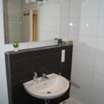 Bad mit Waschbecken, Spiegel und Duschbereich