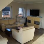 Wohnzimmer mit Ledersofa, Sessel, TV und Glaswand