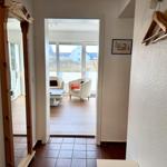 Eingangsbereich mit Spiegel und Blick in Wohnzimmer mit Sitzgelegenheiten.