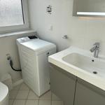 Badezimmer mit Waschmaschine, Waschtisch und Toilette