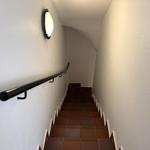 Treppenhaus mit dunkler Handlauf und runden Wanduhr