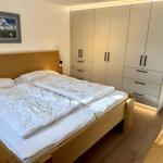 Schlafzimmer mit Doppelbett, Kleiderschrank und Wandbild.