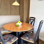 Runder Holztisch mit Stühlen und Sitzbank an Holzwand.