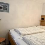 Schlafzimmer mit Bett, Wandbild und Kleiderständer.