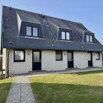 Ferienhaus mit drei Eingängen und Dachfenstern, weiß verputzt mit dunklem Dach.