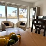 Esszimmer mit Blick auf Wohnbereich und TV. Tisch mit Obst und Sitzgelegenheiten.