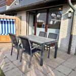 Terrasse mit Tisch und Stühlen sowie Strandkorb.