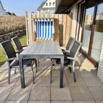 Terrasse mit Tisch, vier Stühlen und Strandkorb.