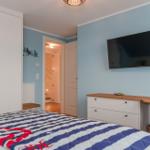 Schlafzimmer mit Bett, Kleiderschrank, TV und Schreibtisch.
