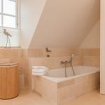 Bad mit Badewanne, Fenster und Holzwaschbecken.