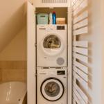 Wäschetrockner und Waschmaschine in einem Schrank neben einer Badewanne.