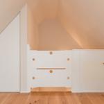 Dachschrägen Raum mit weißem Schrank und Holzboden