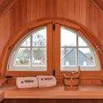 Holzsauna mit Badekorb und Fenster. Handtücher mit Logo liegen bereit.