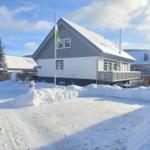 Schneebedecktes Haus mit Balkon und Fahnenmast im Winter.